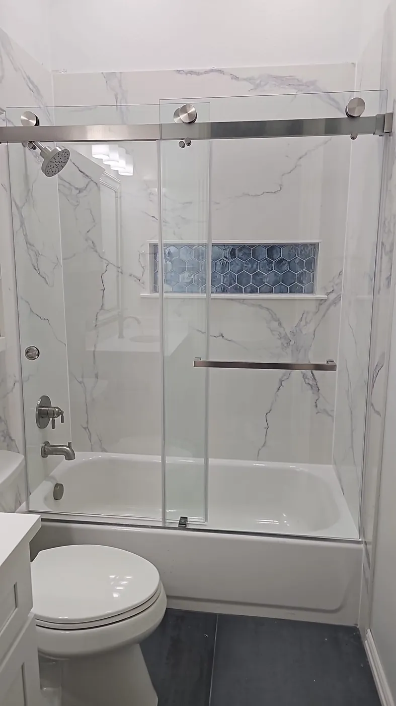 Bathtub replacement with stone-look surround, Delta brushed nickel system, sliding glass door, blue niche inlay, slate flooring and new vanity