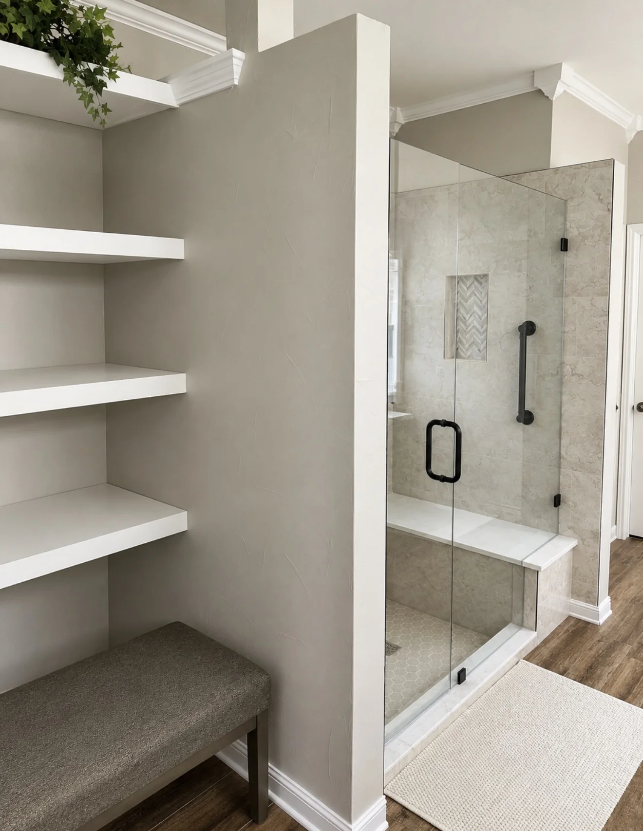 Tub-to-shower conversion with stone walls, built-in bench, black grab bar, custom glass and adjacent open linen shelving