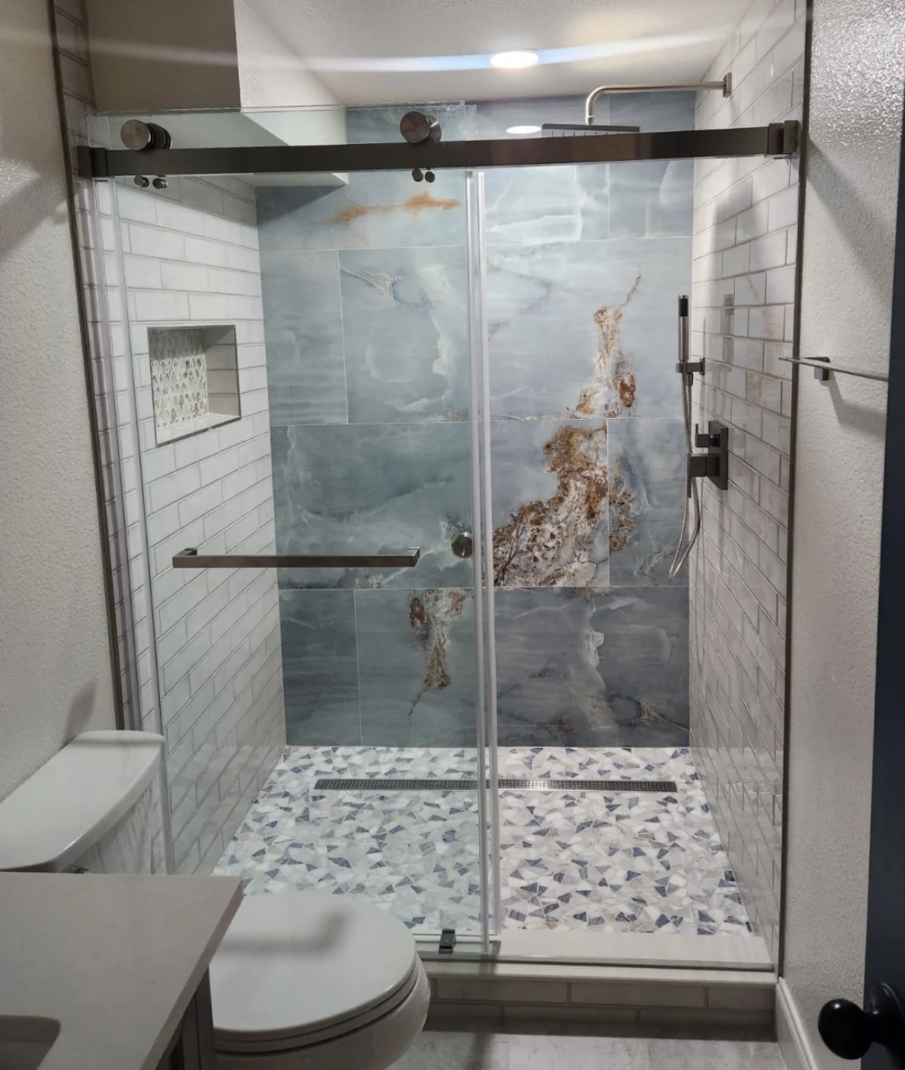 Full bathroom remodel with blue accent shower wall, subway tile, farmhouse sliding glass, mosaic floor, soaking tub and updated vanity