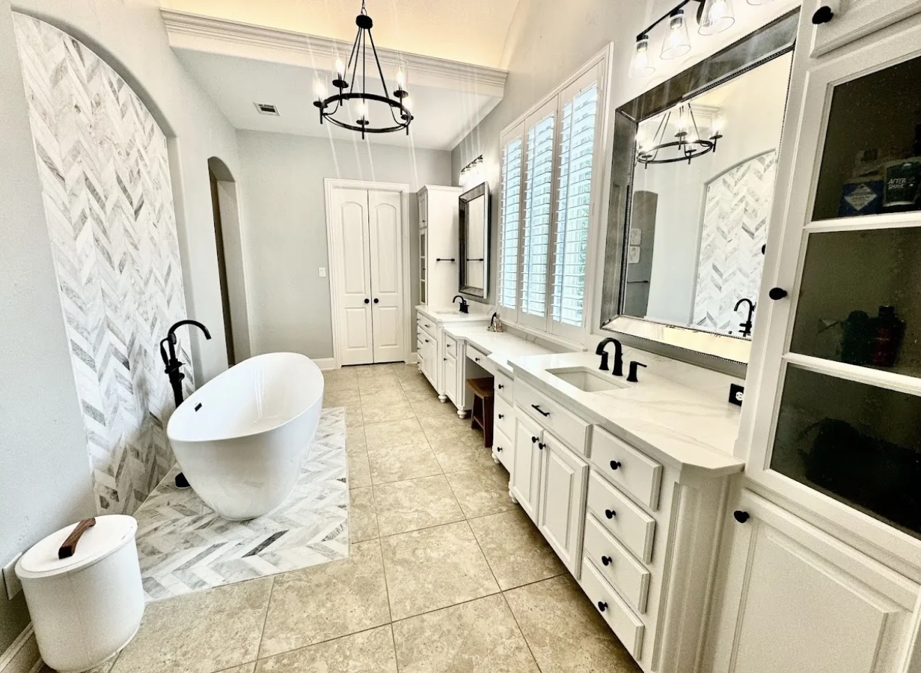 Full primary bathroom remodel with freestanding tub, white vanities, quartz countertops, custom mirrors and built-in cabinetry